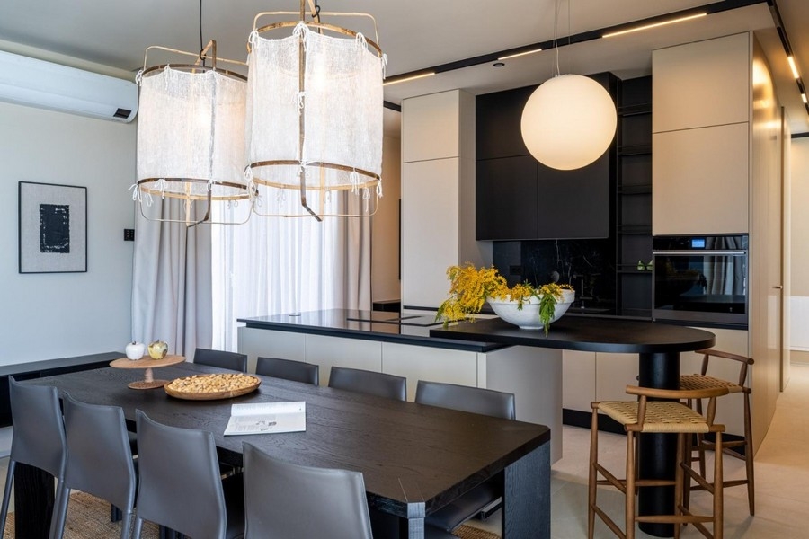 Tavolo da pranzo con lampade di design davanti alla cucina aperta