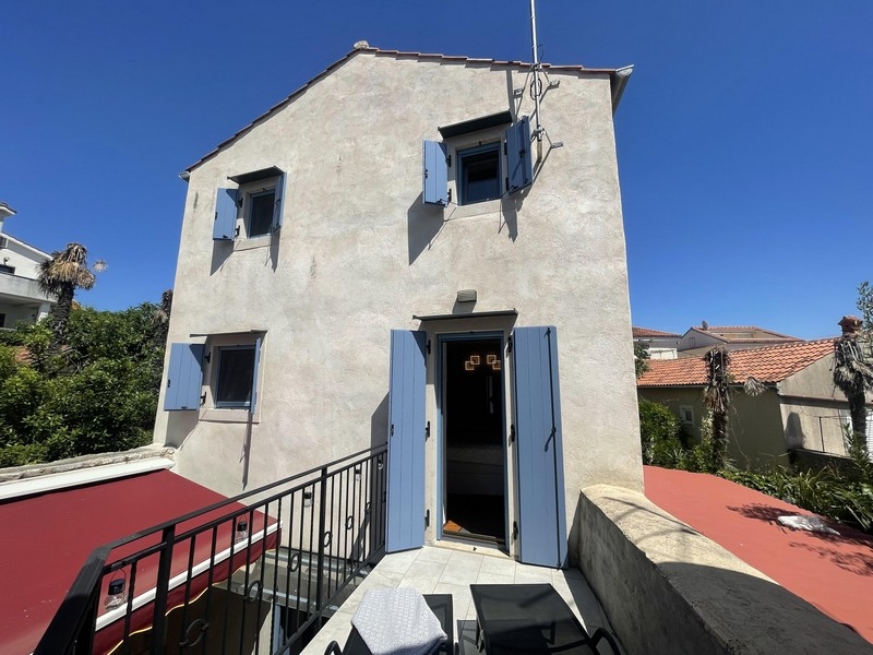 Casa in pietra con persiane azzurre e terrazza sul tetto a Krk