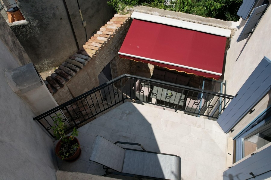 Terrazza con tenda da sole rossa e zona salotto nel cortile interno