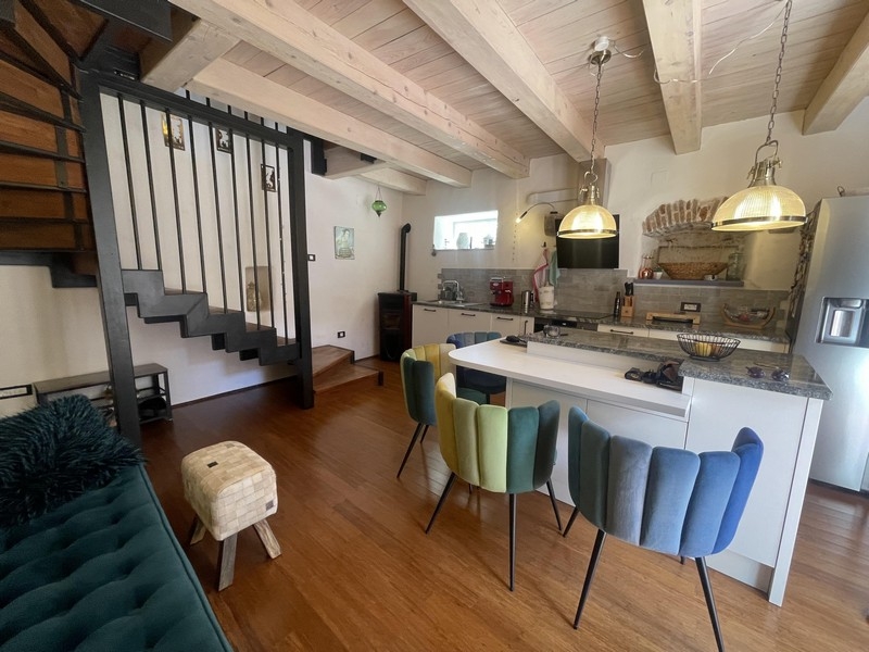 Zona giorno aperta con cucina e soffitto a travi di legno