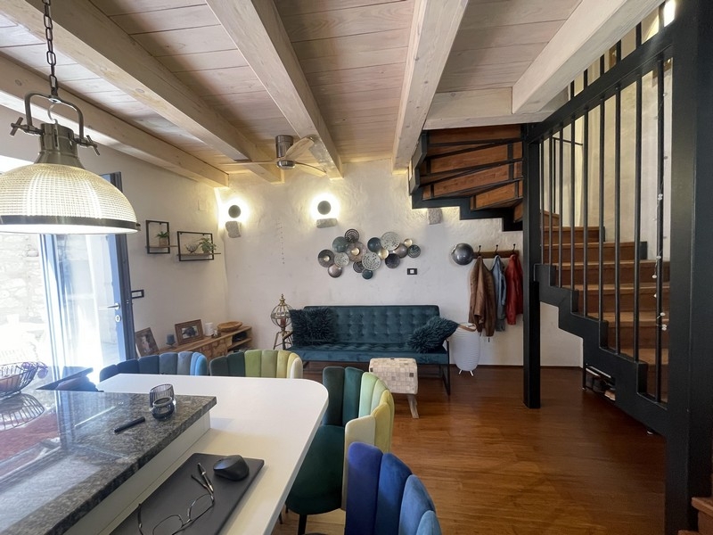 Soggiorno con divano, isola cucina e scala per il piano superiore