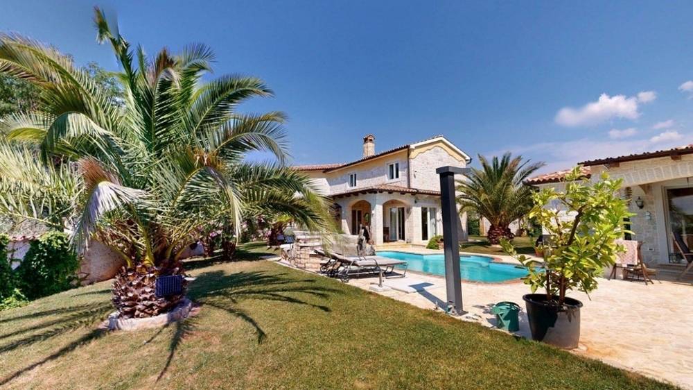 Giardino mediterraneo con palme e piscina davanti alla casa