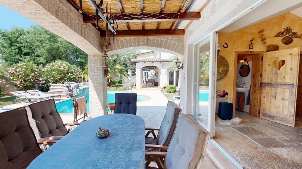 Terrazza coperta della konoba con tavolo da pranzo e vista sulla piscina