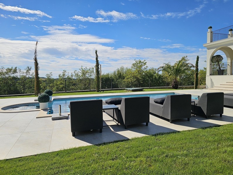 Terrazza della piscina con mobili lounge e prato della villa a Buje