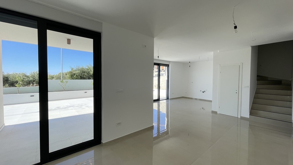 Soggiorno con porta della terrazza e scala per il piano superiore a Vodice