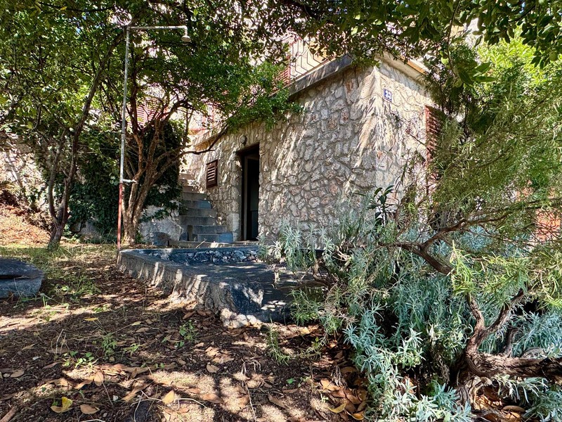 Casa in pietra nel verde con scala verso l'ingresso