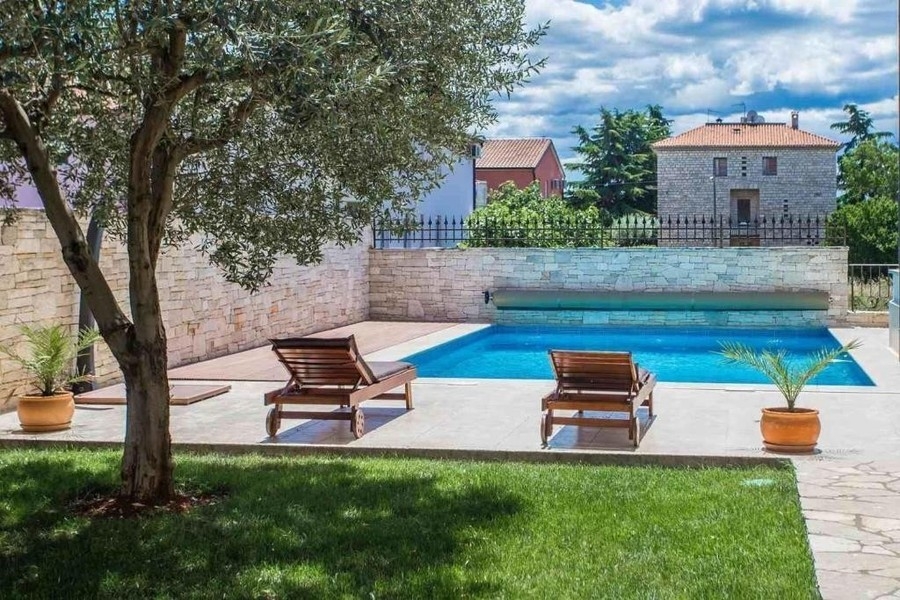 Piscina riscaldata con lettini in giardino