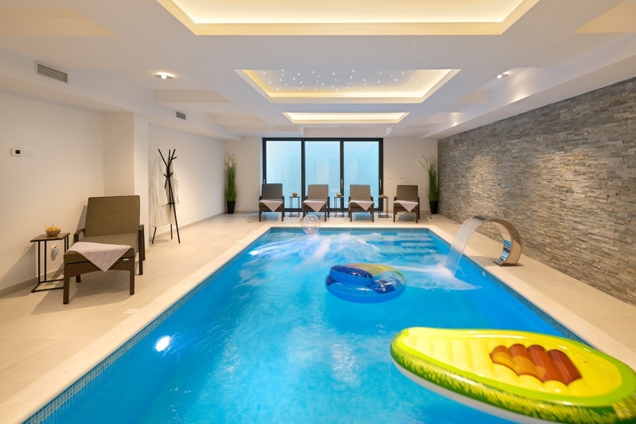 Piscina interna illuminata con parete in pietra naturale