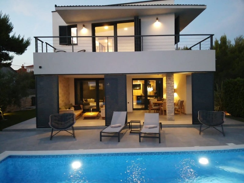 Fronte della casa con terrazza e piscina illuminata