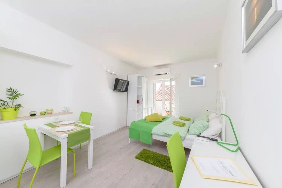 Monolocale con blocco cucina e accenti verdi