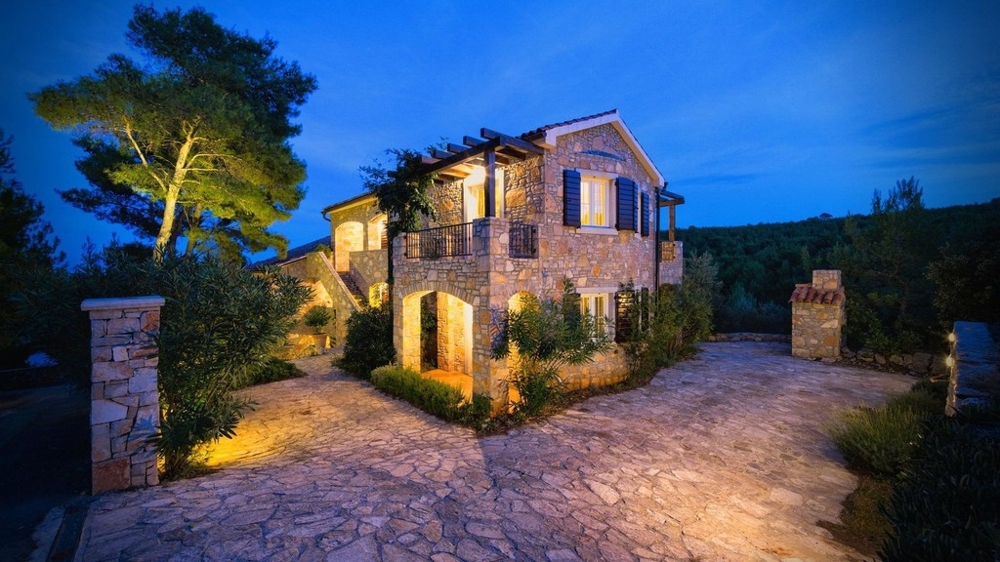 Casa in pietra la sera con cortile illuminato