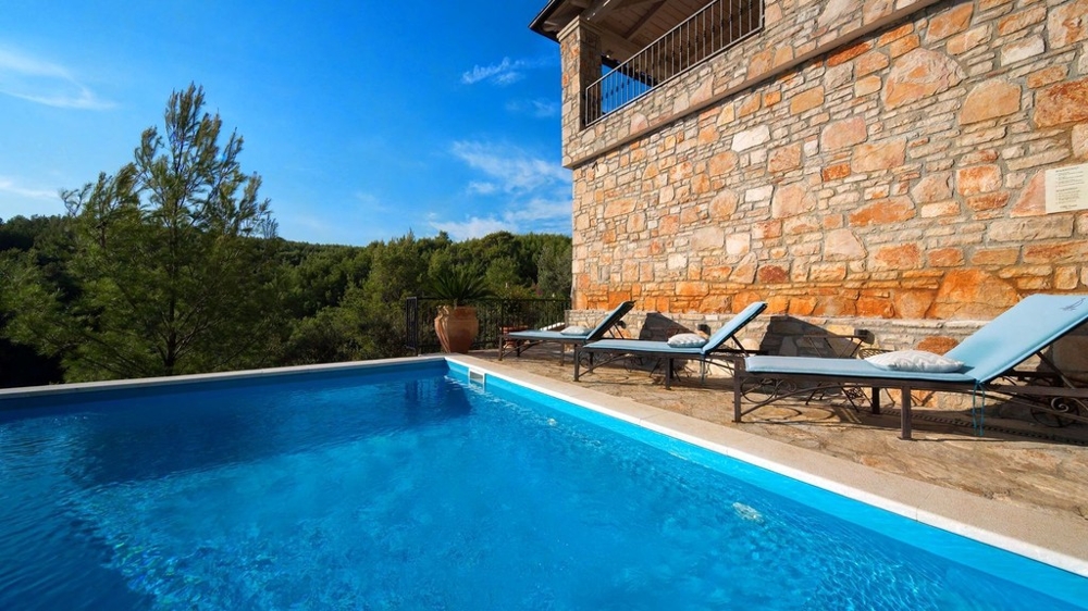 Piscina con lettini presso la facciata in pietra