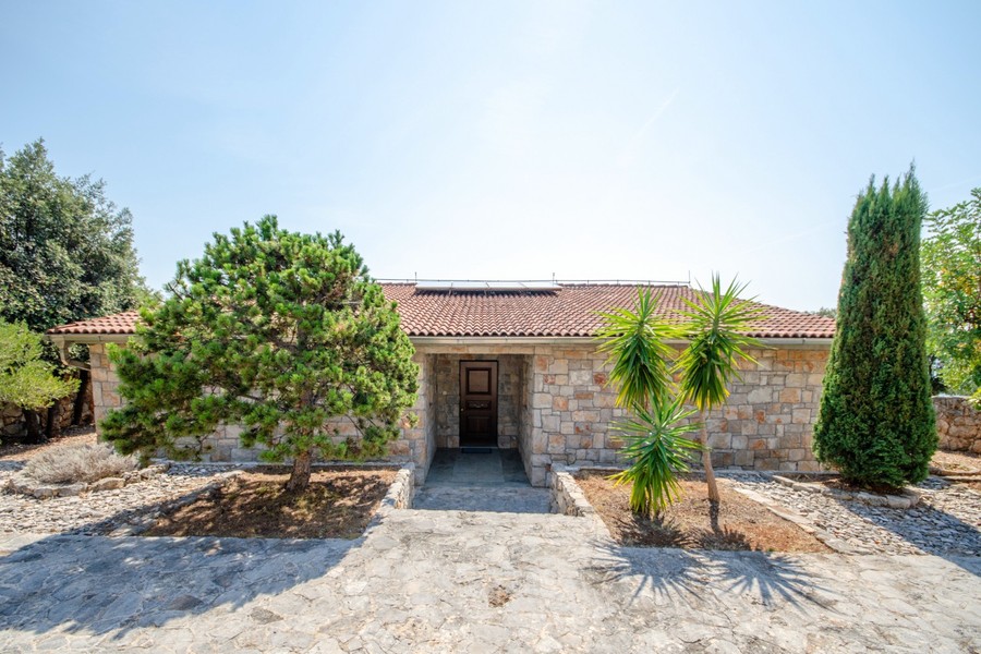 Ingresso della villa in pietra con palme e cipressi
