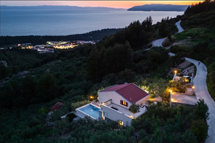 Villa sul pendio con piscina illuminata la sera
