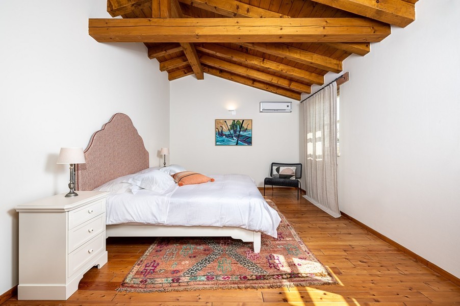 Camera da letto con soffitto a travi di legno, tappeto e aria condizionata
