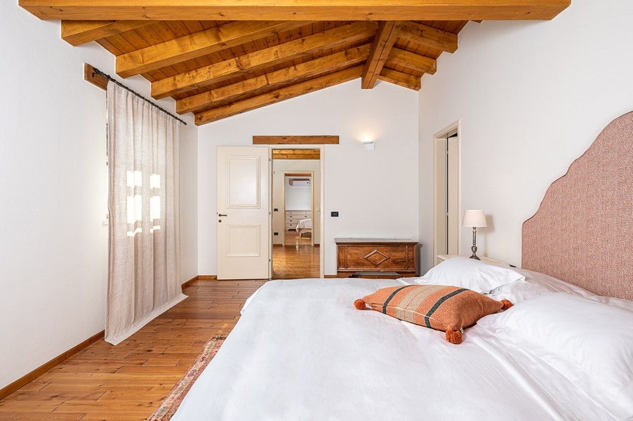 Letto matrimoniale con cuscino arancione e porta aperta