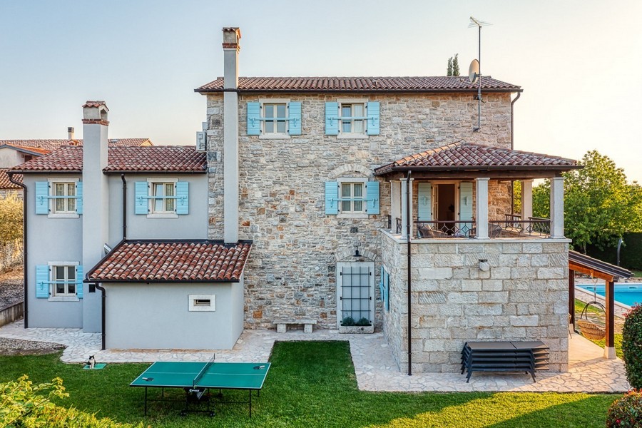 Vista laterale della casa in pietra con prato e camini