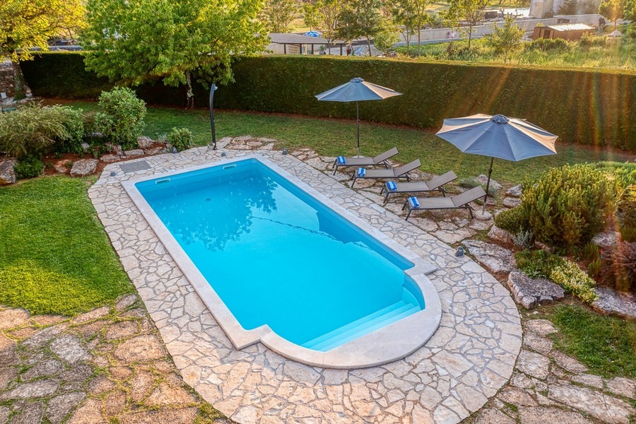 Piscina con lettini, ombrelloni e prato