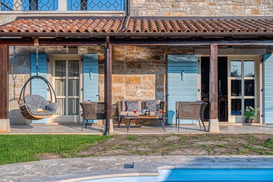Terrazza coperta con poltrona sospesa e mobili in rattan