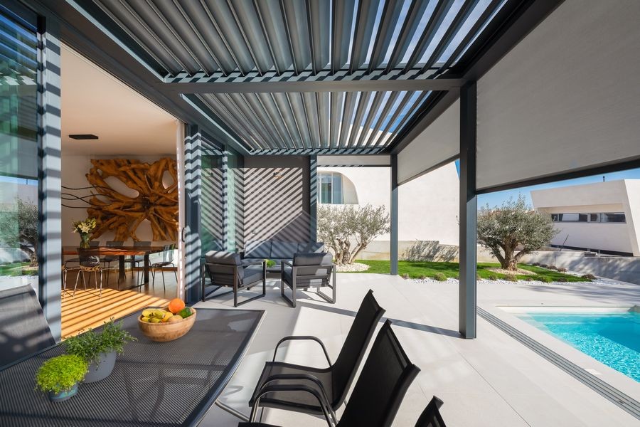 Terrazza coperta con tavolo da pranzo accanto alla piscina