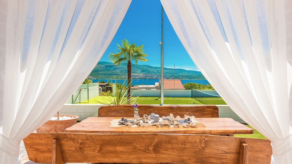 Terrazza coperta con tavolo in legno e tende