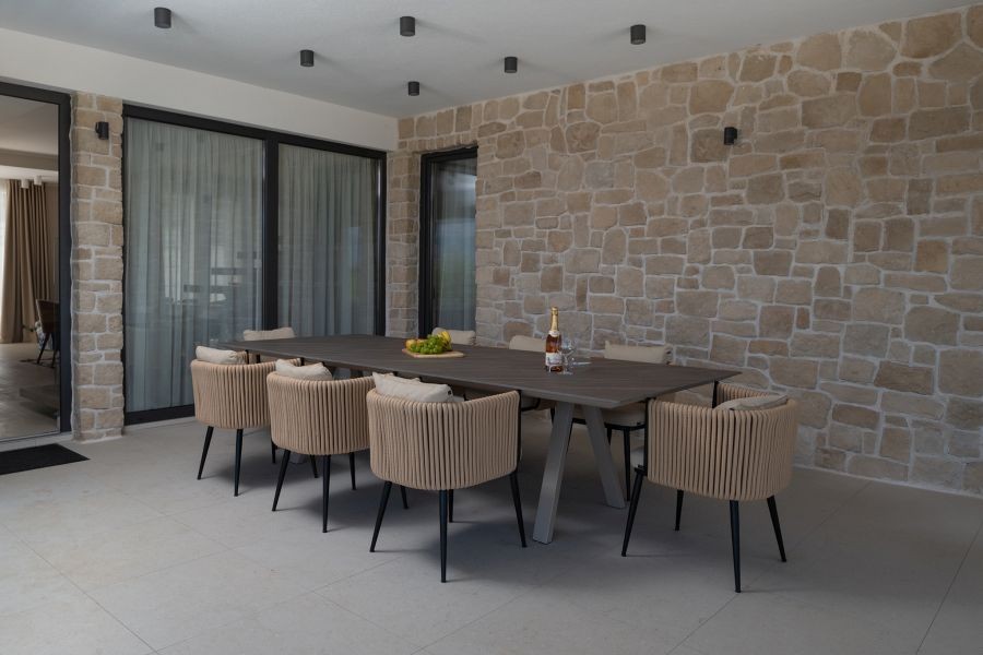 Terrazza coperta con tavolo da pranzo e parete in pietra naturale