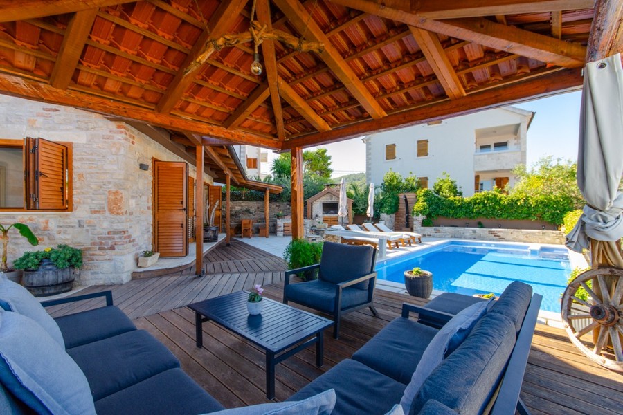 Terrazza in legno coperta con salotto accanto alla piscina