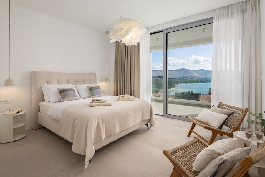 Camera da letto con facciata in vetro e vista mare