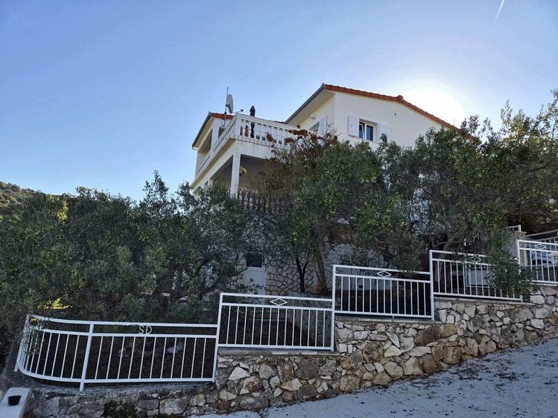 Casa sul pendio con balconi e recinzione verso la strada