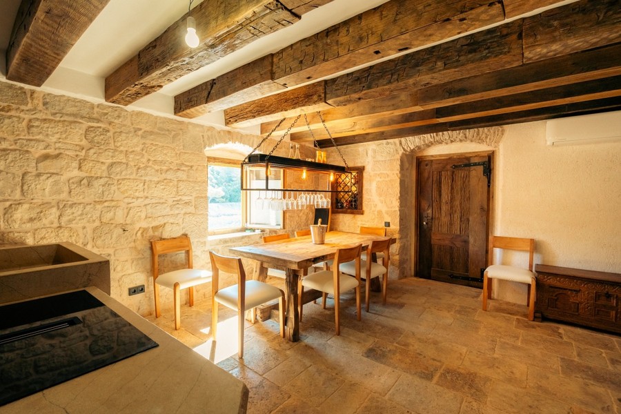 Zona pranzo con tavolo in legno e angolo cottura