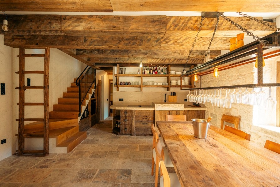 Soggiorno con scala, scaffali e soffitto con travi di legno