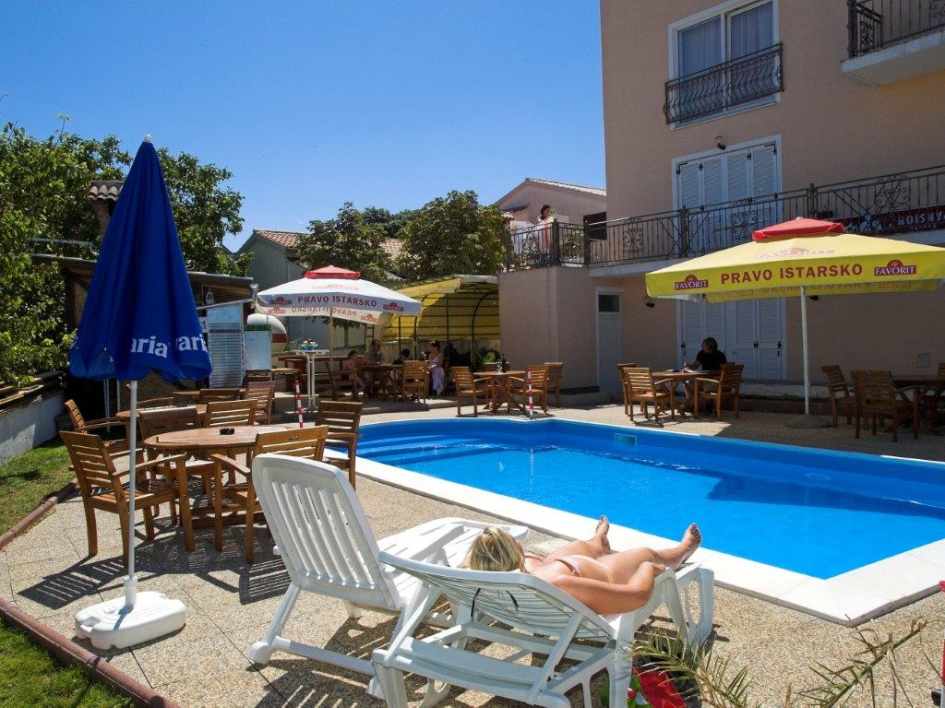Piscina con ombrelloni e lettini nella pensione-hotel vicino a Pula