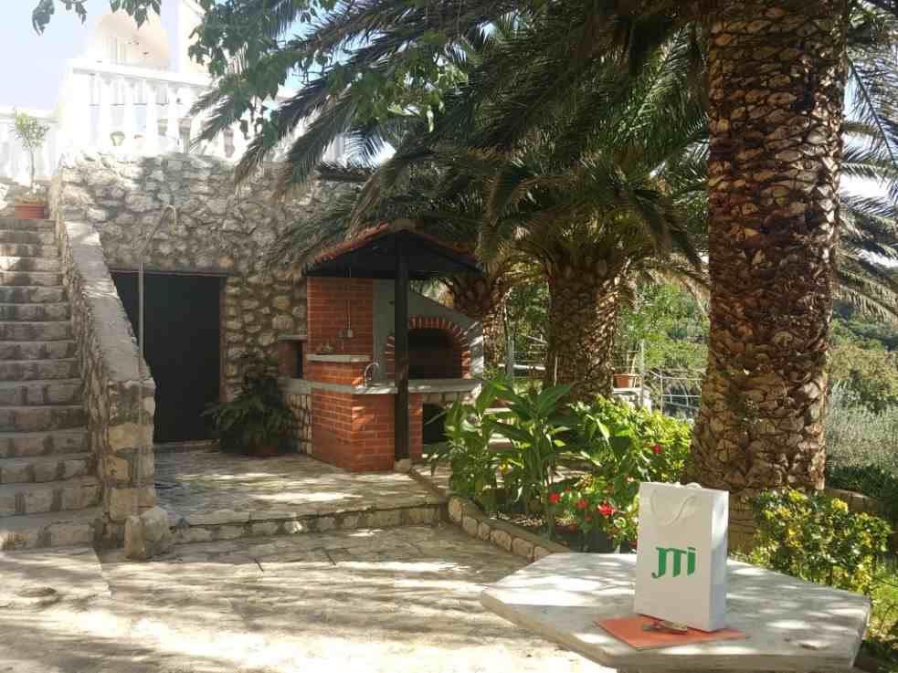 Il cortile della villa con appartamenti in vendita a Pag è sistemato e piantumato in stile mediterraneo.