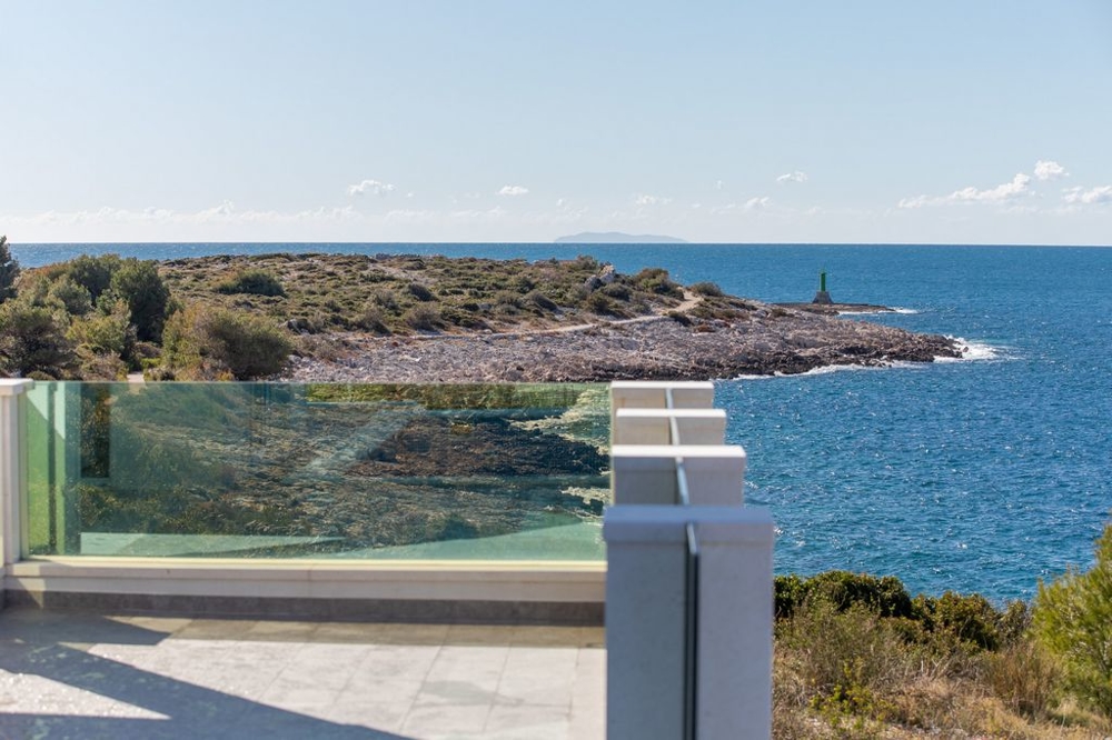 Vista oltre il parapetto in vetro sulla costa rocciosa con faro