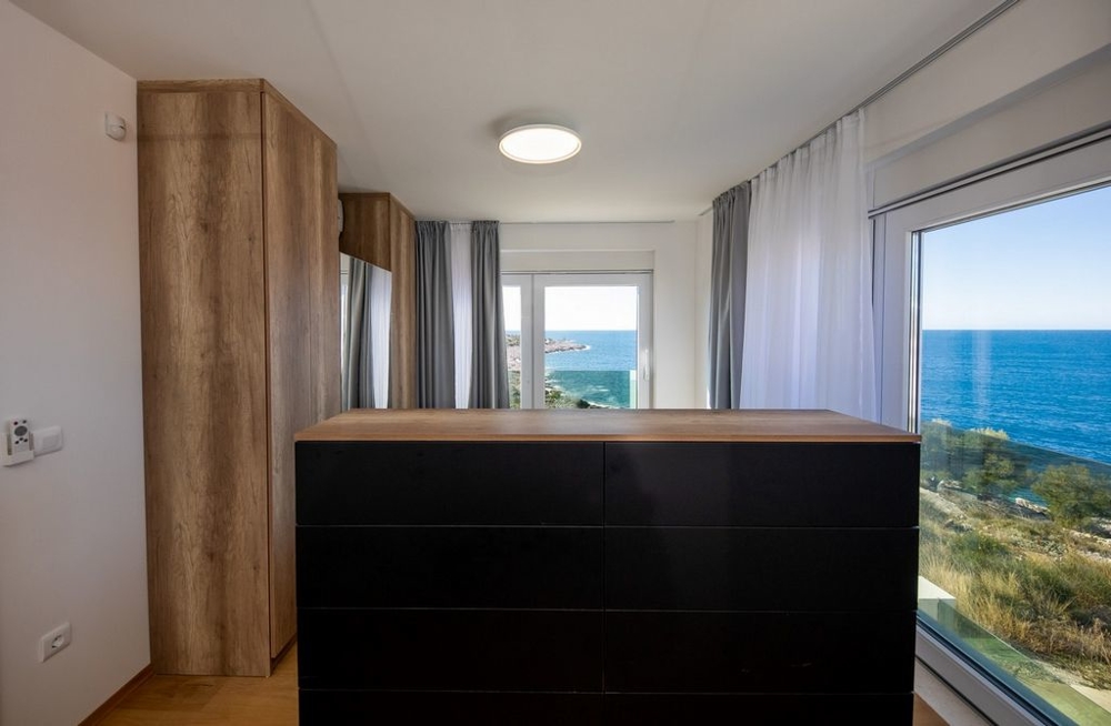 Camera da letto con cassettiera e tende davanti alla vista mare